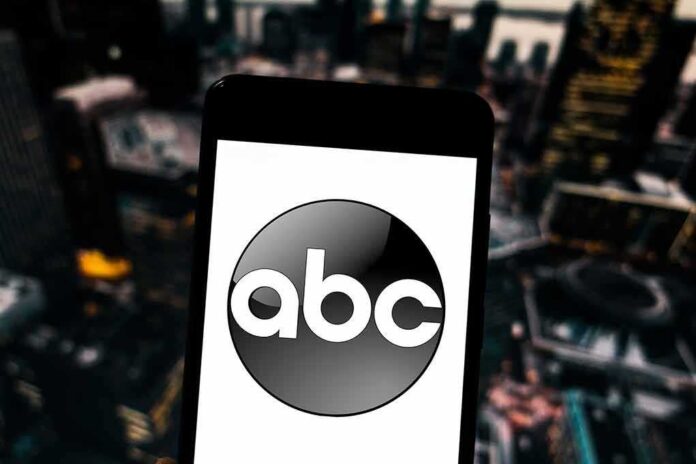 A smartphone displaying the ABC logo against a blurred urban background
