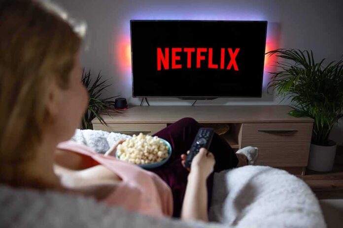 Person watching Netflix on a TV while holding a bowl of popcorn