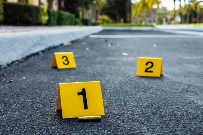 shutterstock_2182405839 Crime scene markers on asphalt with bullet casing.