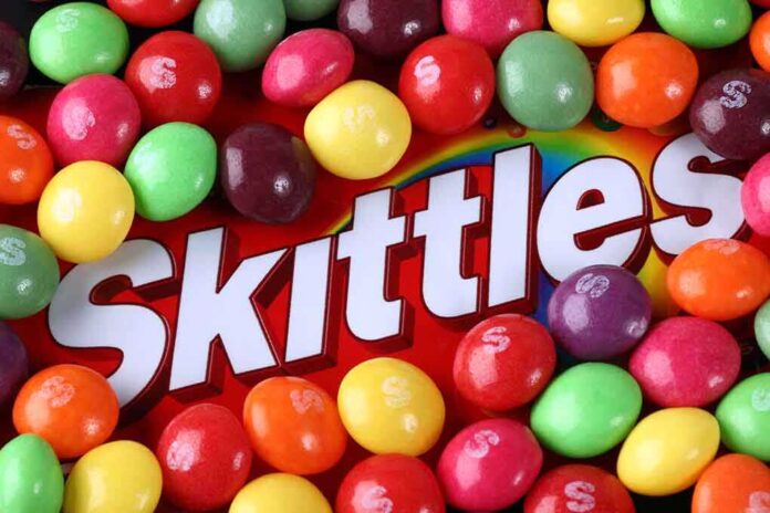 shutterstock_222204877.jpg A colorful assortment of Skittles candies surrounding the Skittles packaging