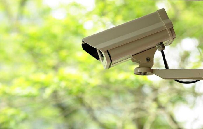 A security camera mounted outdoors with a blurred green background