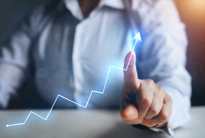 1936001935 Person pointing at an upward trend line graph.