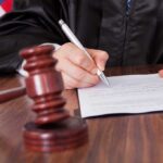 CEO Assassin Charges VANISH — What Really Happened? A judge signing a legal document with a gavel in the foreground