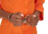 Hands of a person in handcuffs wearing an orange jumpsuit