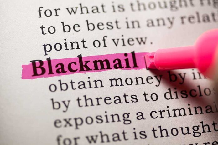 Close-up of a dictionary page with the word blackmail highlighted in pink