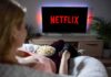 Person watching Netflix on a TV while holding a bowl of popcorn