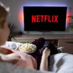 Person watching Netflix on a TV while holding a bowl of popcorn