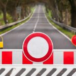 Traffic barrier with a red and white sign blocking a road