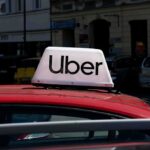 Uber sign on top of a red taxi in an urban setting