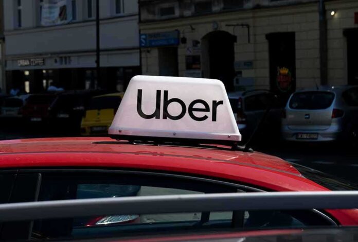 Uber sign on top of a red taxi in an urban setting