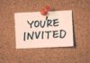 A note pinned to a corkboard that says YOU'RE INVITED