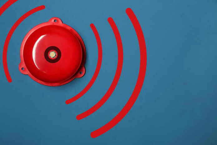 1311134939 Red alarm bell on a blue background.