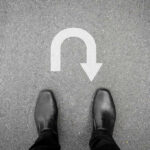 Late Vote Flip Shocks New Jersey Feet in black shoes facing U-turn road marking.