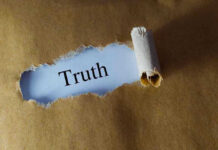 Ripped paper reveals word truth underneath brown surface