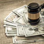 $2 Million Jury Bombshell Hits Doctors Gavel on a pile of hundred-dollar bills.