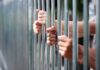 Hands gripping metal prison bars