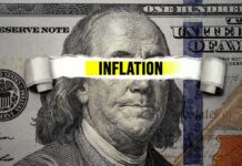 A torn paper strip with the word INFLATION over a hundred dollar bill featuring Benjamin Franklin