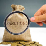Hand holding magnifying glass over sack labeled Sanctions.