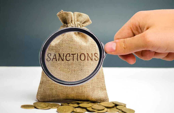 Hand holding magnifying glass over sack labeled Sanctions.