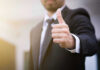 Person in suit giving thumbs up gesture.