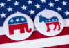 Republican elephant and Democrat donkey on American flag.