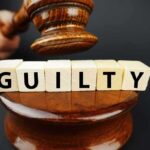 A gavel striking down next to wooden blocks spelling 'GUILTY'