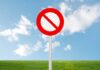 A no entry sign on a grassy field under a clear blue sky