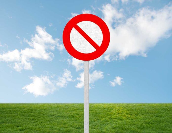A no entry sign on a grassy field under a clear blue sky