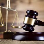 A wooden gavel and scales of justice on a wooden surface