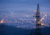 Night view of a city skyline with power lines in the foreground