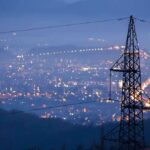 Night view of a city skyline with power lines in the foreground