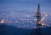 Night view of a city skyline with power lines in the foreground