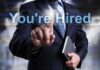 Businessman pointing at a digital display that says 'You're Hired'