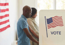 People voting at polling booths with American flag.