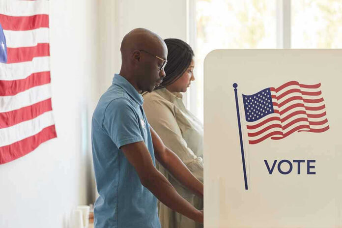 People voting at polling booths with American flag.