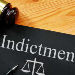 BOMBSHELL Indictment Rocks Fauci’s Inner Circle Gavel next to indictment document on wooden table.