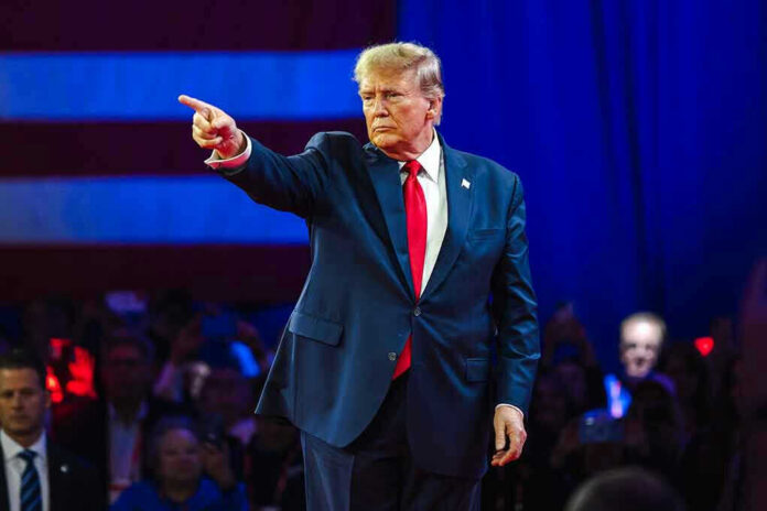 Person in suit pointing during a public event.