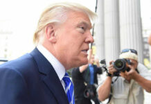 Man in suit with photographers in background.