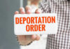 Hand holding sign with Deportation Order text.