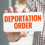 DHS Ships Migrants To Africa Hand holding sign with Deportation Order text.