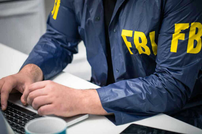 Person in FBI jacket typing on a laptop.