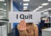 Person holding a sign that says I Quit in an office setting