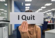 Person holding a sign that says I Quit in an office setting