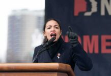 A woman passionately speaking at a podium during a rally