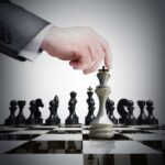 King Charles Takes Congress—Critics ERUPT A hand moving a chess piece on a chessboard