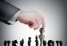 A hand moving a chess piece on a chessboard