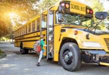 A child with a backpack boarding a yellow school bus