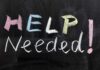 Chalkboard with the words HELP NEEDED written in colorful chalk