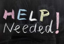 Chalkboard with the words HELP NEEDED written in colorful chalk