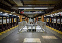 Subway station platform with directional signs overhead.